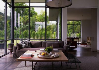 Lux couch and oversized square coffee table with Floor to ceiling windows overlooking the garden