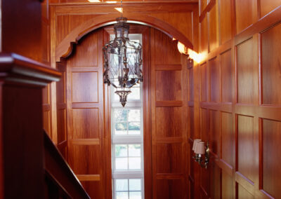 Entryway with vintage pendant light surrounded by craftsman wood paneled walls and staircase